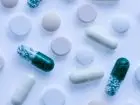Praca grupa Farmacol - symboliczne tabletki i kapsułki na białym blacie
