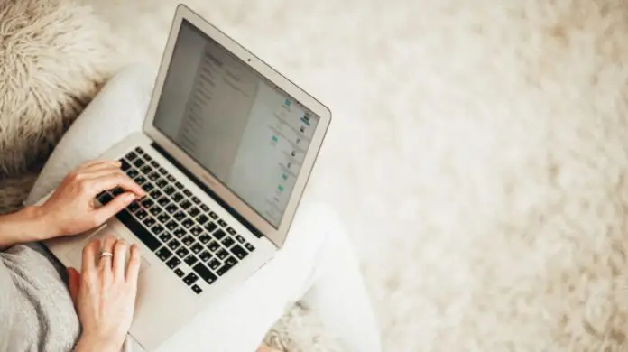 Praca online - laptop położony na kolanach