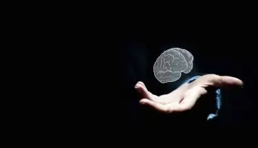 Psychiatra - grafika ludzkiego mózgu w dłoni na ciemnym tle