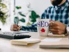 SEO copywriter - mężczyzna przy biurku z kubkiem z napisem SEO