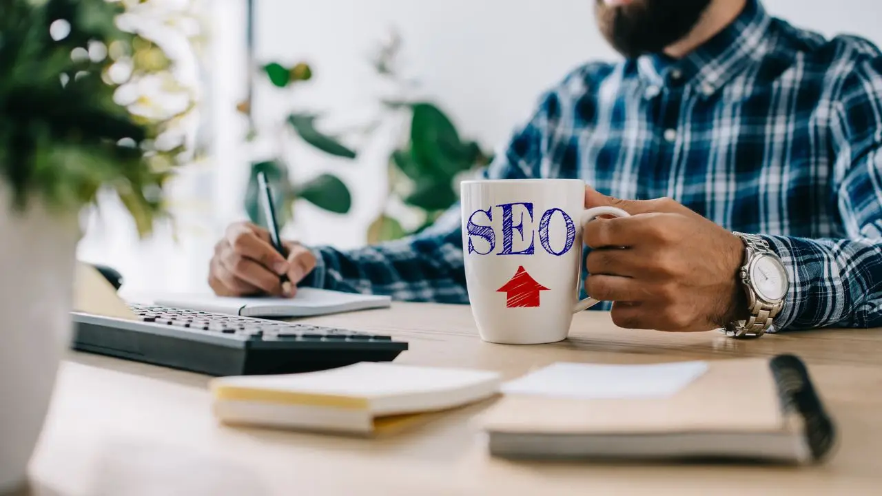 SEO copywriter - mężczyzna przy biurku z kubkiem z napisem SEO