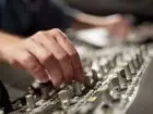 Jak zostać lektorem radiowym - zbliżenie na dłonie mężczyzny ustawiającego głośność na urządzeniu radiowym