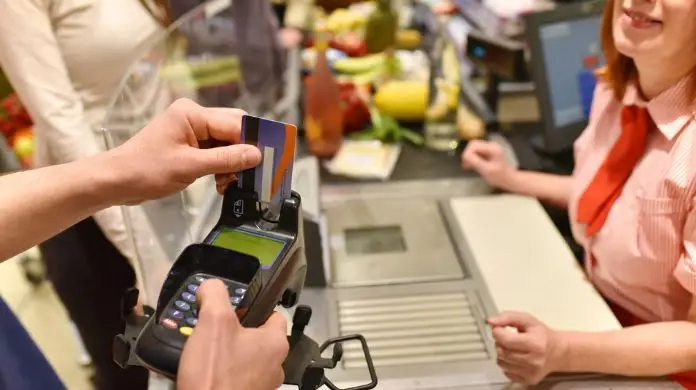 Praca Lidl - symboliczne zdjęcie przedstawiające moment dokonania płatności przy kasie w markecie i kasjerkę obsługującą klientów