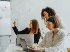 Jak napisać plan strategiczny - trzy kobiety w trakcie planowania, wykorzystują komputery i tablicę