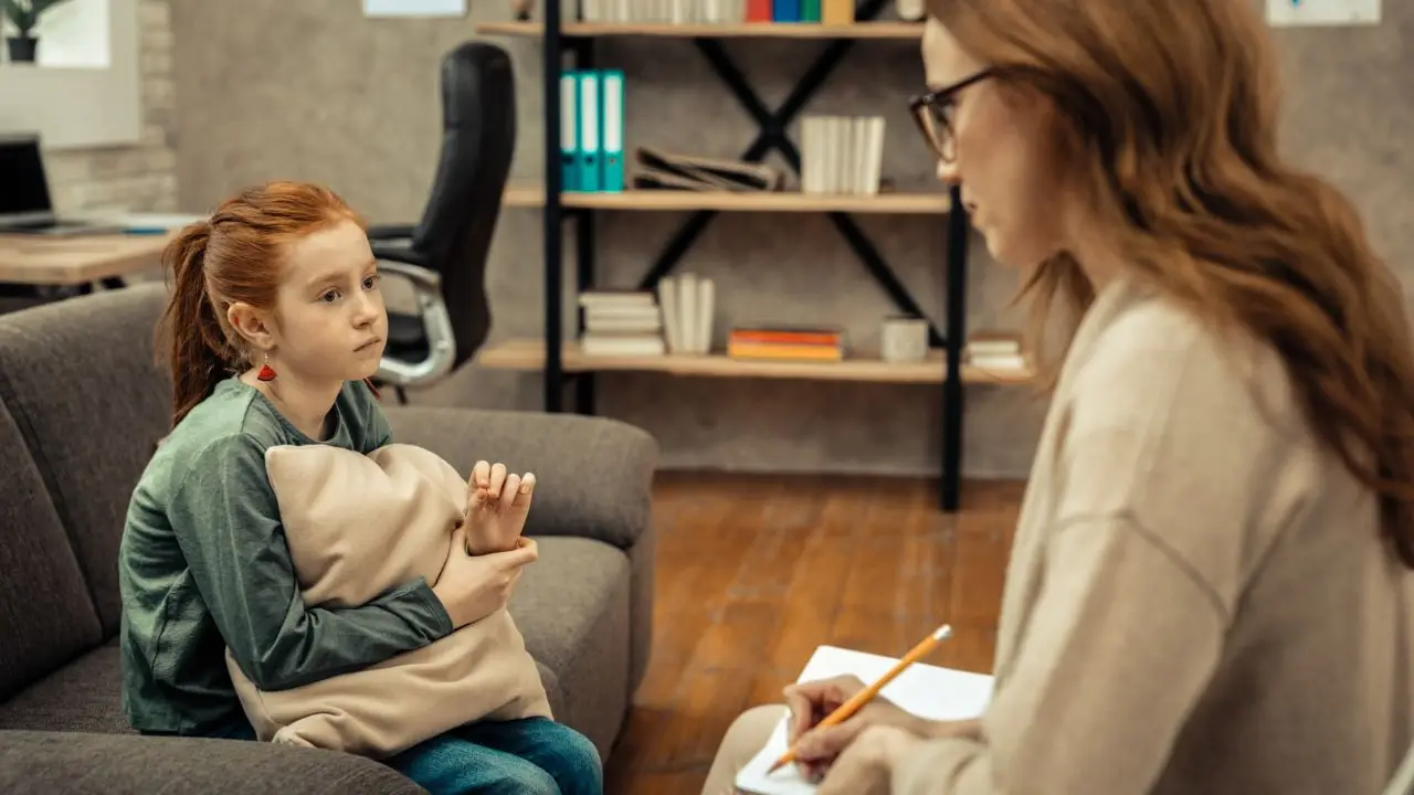 Pedagogika co po studiach - kobieta rozmawiająca z dzieckiem w gabinecie