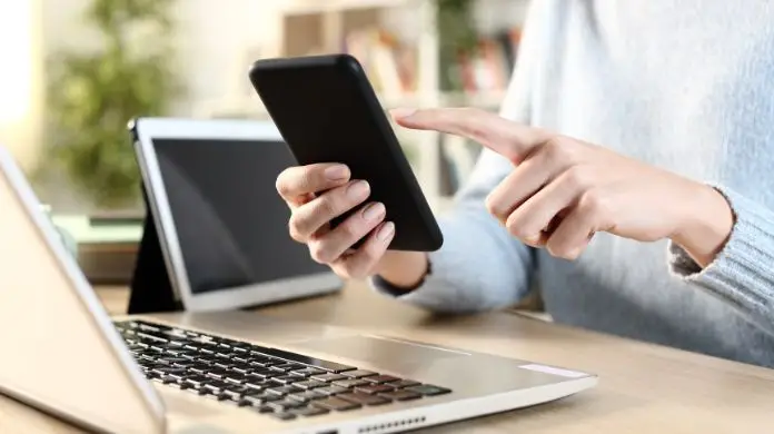 Zakaz TikToka dla pracowników KE - osoba korzystająca z telefonu podczas pracy przy komputerze