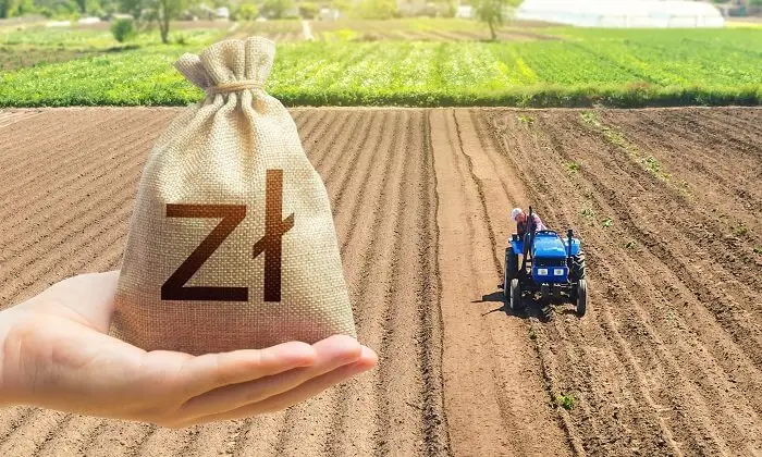 Traktor na polu oraz ręka trzymająca worek z pieniędzmi