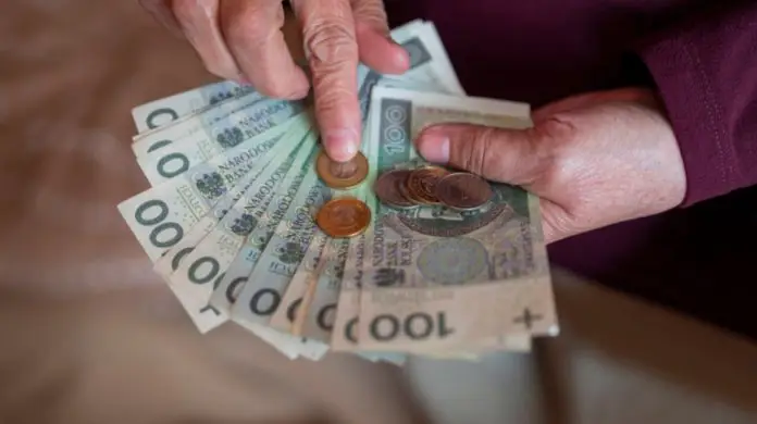 Koniec części emerytur bez podatku - emeryt liczący banknoty i bilon w dłoniach