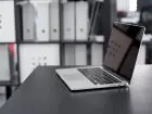 Praca PKO BP - laptop na biurku na tle segregatorów