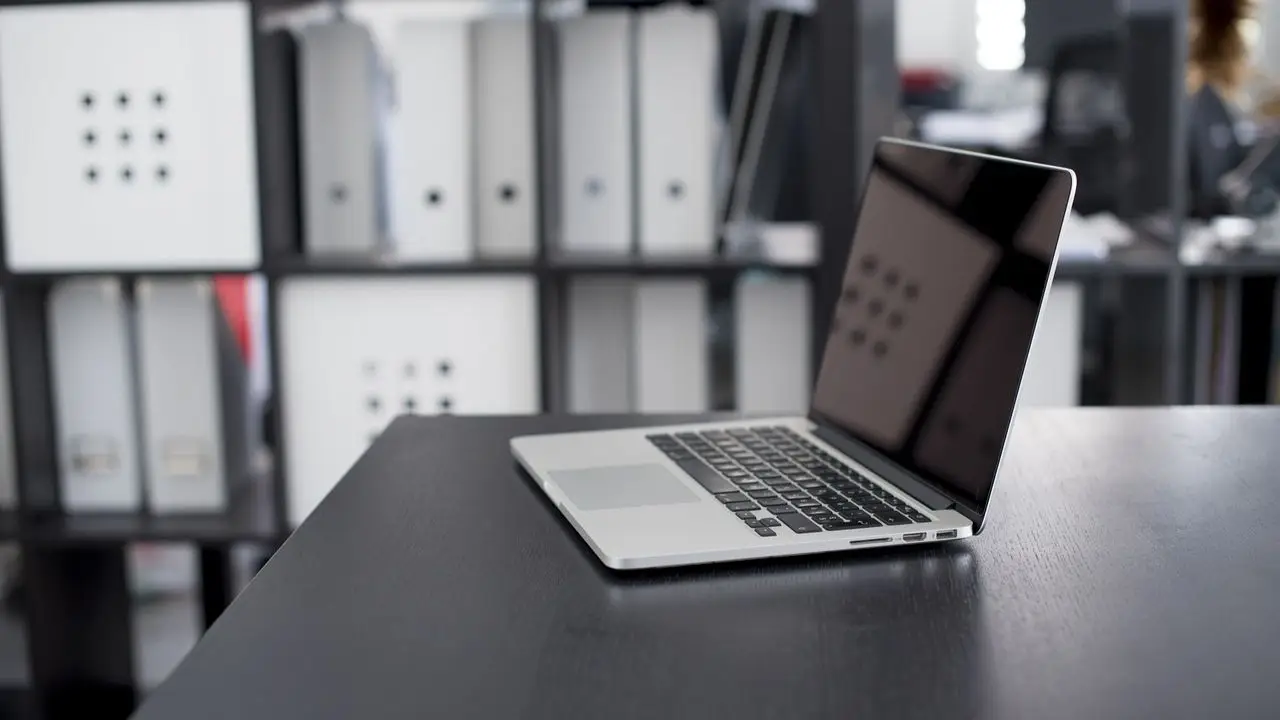 Praca PKO BP - laptop na biurku na tle segregatorów