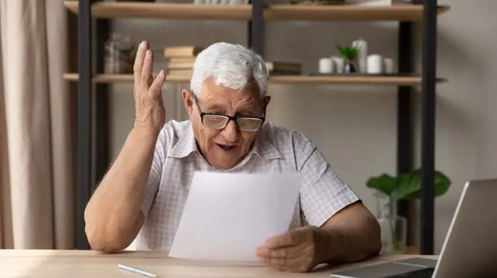 Zdziwiony emeryt czytający otrzymany dokument
