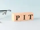 Rozliczenie PIT a korekta - jak naprawić błąd - okulary, długopis i napis "PIT" ułożony z klocków