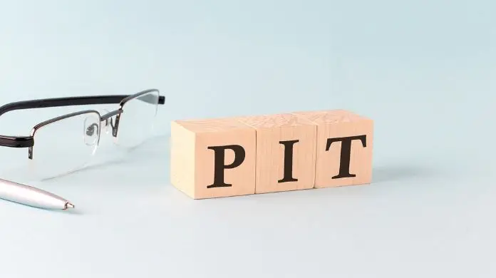 Rozliczenie PIT a korekta - jak naprawić błąd - okulary, długopis i napis "PIT" ułożony z klocków
