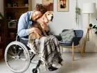 Świadczenie wspierające - osoba z niepełnosprawnością poruszjaąca się na wózku przytulająca psa