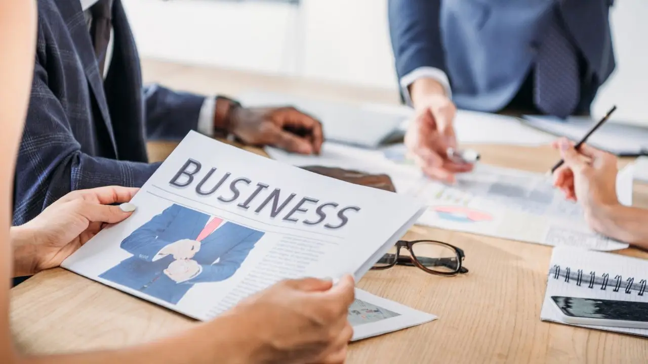 Biznes za 10 000 - gazeta z napisem business trzymana w dłoniach w biurze