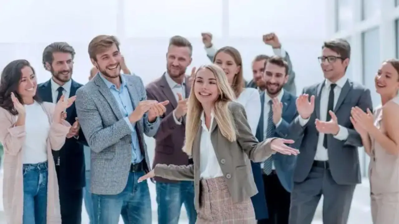 Co powiedzieć po otrzymaniu awansu - pracownicy stojący w grupie, gratulujący koleżance w pracy