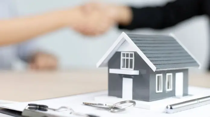 Wyższe ceny mieszkań a Bezpieczny Kredyt 2% - figurka domu postawiona na dokumentach