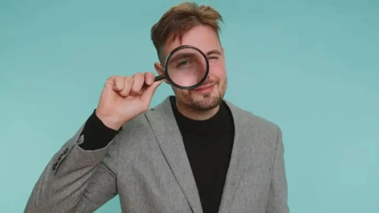 Elegancko ubrany mężczyzna patrzący przez lupę