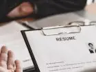 Jak rekrutować do pracy - Zdjęcie przedstawiające dłonie dwóch osób, jedna trzyma wydrukowane CV