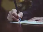 Ręka kobiety zapisuje w małym białym notatniku