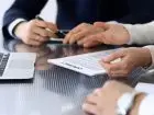 Jak długo trwa rejestracja spółki - ludzie skupienie przy biurku z dokumentami i laptopem