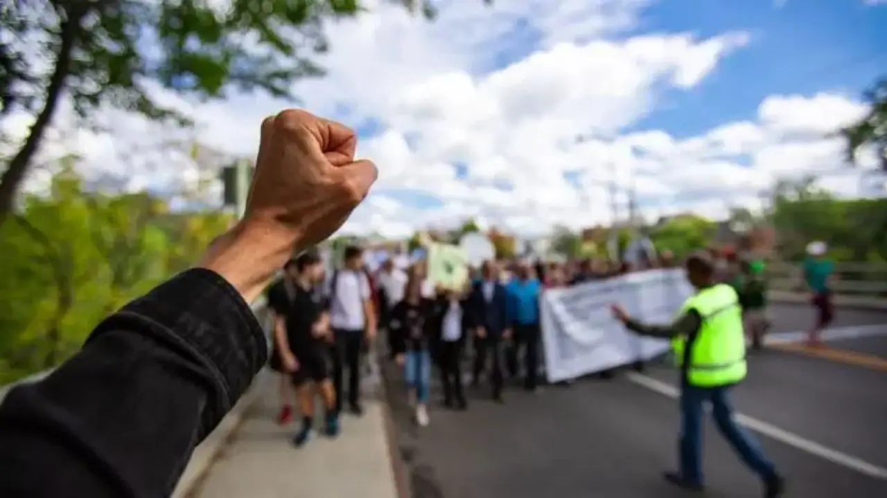 Protest pracowników budżetówki - pięść uniesiona w górę, w tle protestujący