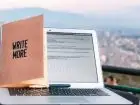 Jakie studia skończyć aby zostać copywriterem - otwarty laptop, a na nim postawiony notes z napisem "write more"