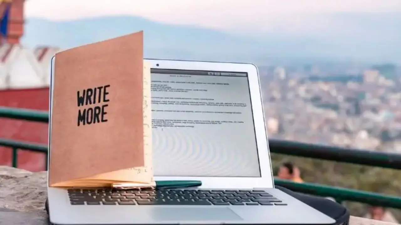 Jakie studia skończyć aby zostać copywriterem - otwarty laptop, a na nim postawiony notes z napisem "write more"