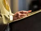 Emerytury księży w górę - Ręce katolickiego księdza - czyta biblię.