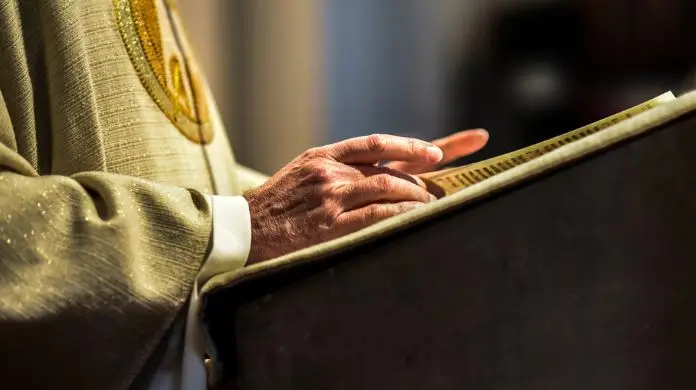Emerytury księży w górę - Ręce katolickiego księdza - czyta biblię.