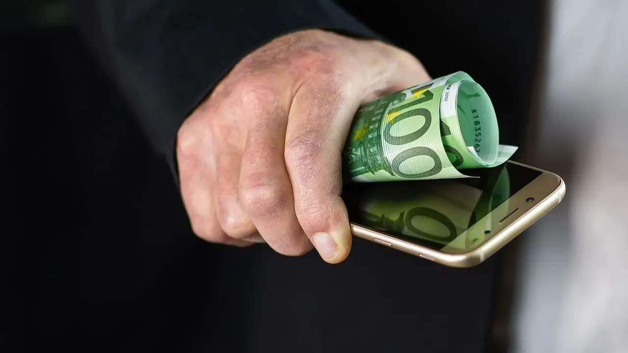 Jak bronić się przed nieuczciwą konkurencją - banknot i telefon w dłoni