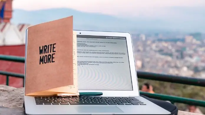 Jakie studia skończyć aby zostać copywriterem - otwarty laptop, a na nim postawiony notes z napisem "write more"