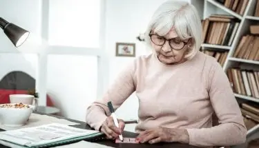 Kobieta w wieku emerytalnym siedząca przy biurku