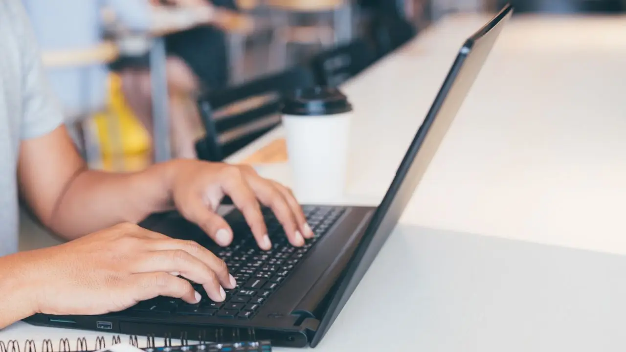 Copywriterka podczas pracy, zbliżenie na jej dłonie na laptopie