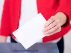 Obietnice wyborcze dla rynku pracy - wybory - kobieta trzymająca kartę wyborczą nad urną