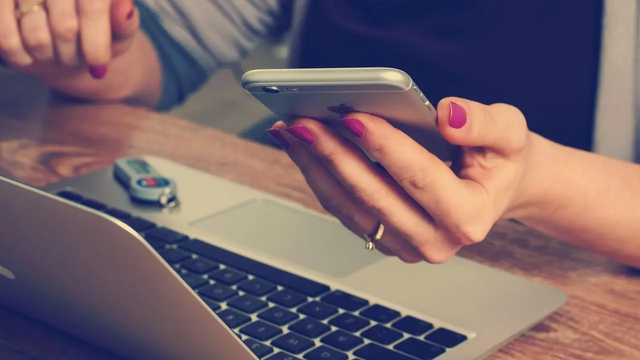 Kobieta przy laptopie z telefonem w dŁoni - zastrzeżenie PESEL