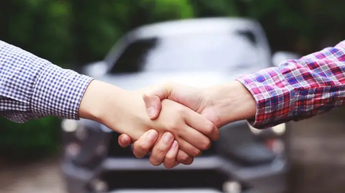 podatek od zakupu samochodu - uścisk dłoni dwóch mężczyzn na tle samochodu