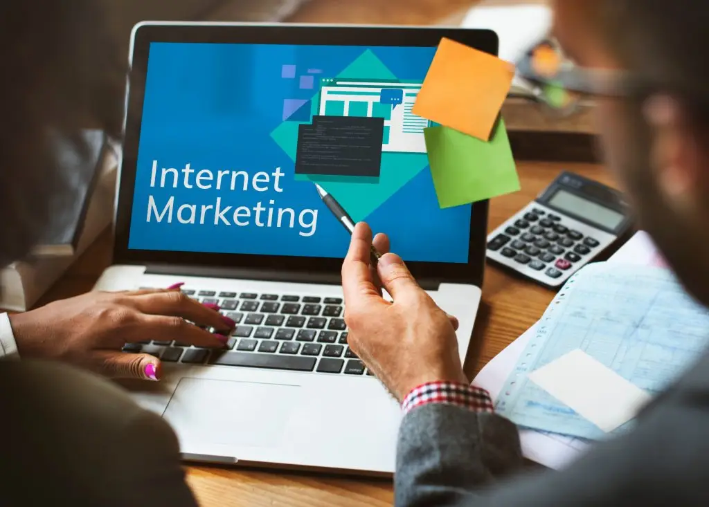 Jak zadbać o marketing internetowy firmy - dwie osoby siedzące przy laptopie z napisem "Internet marketing" na ekranie