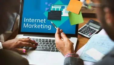 Jak zadbać o marketing internetowy firmy - dwie osoby siedzące przy laptopie z napisem "Internet marketing" na ekranie