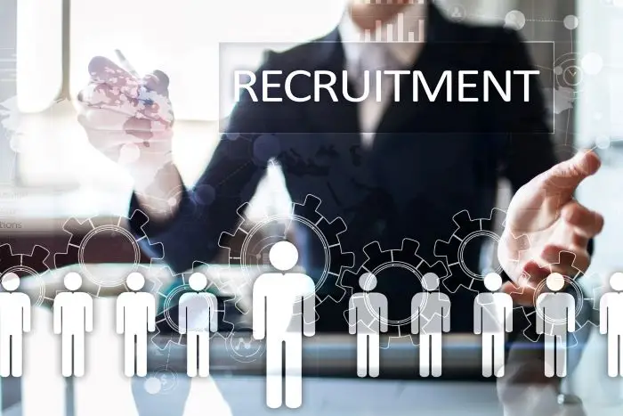 Jakie są koszty rekrutacji - grafika przedstawiająca sylwetki ludzi, na które spogląda kobieta z działu HR