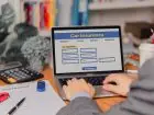 person using a laptop device to access an online car insurance platform customers can compare quotes, With this innovative solution, file claims, and access roadside assistance right.