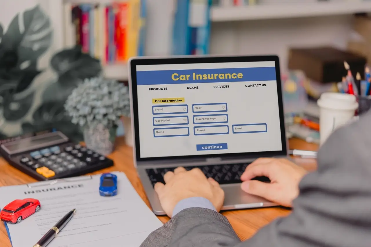 person using a laptop device to access an online car insurance platform customers can compare quotes, With this innovative solution, file claims, and access roadside assistance right.