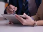 Konsultacje CV - zbliżenie na dłonie osób omawiających plik na tablecie