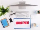 Rekrutacja zdalna - komputer i przybory biurowe na blacie, obok napis recruitment