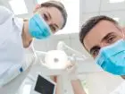 600 zł na dentystę - dentysta i asystentka zaglądający do jamy ustanej pacjenta