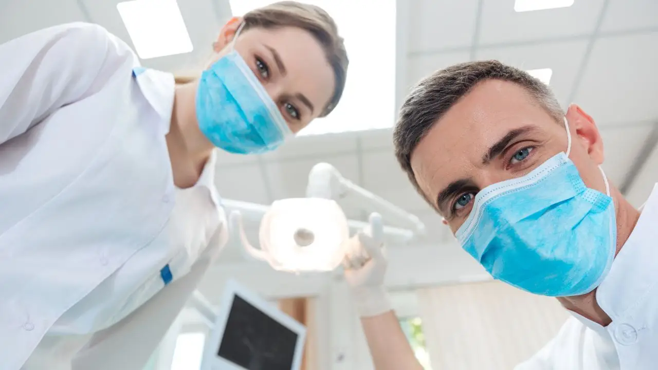 600 zł na dentystę - dentysta i asystentka zaglądający do jamy ustanej pacjenta