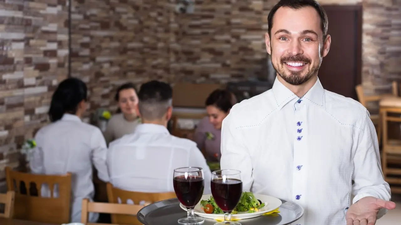 Ile zarabia kelner - kelner trzymający tacę w restauracji