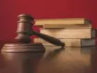 Mobbing KGHM - młotek sędziowski i książki na czerwonym tle