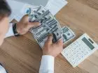Podwyżki dla pracowników - mężczyzna przy biurku liczący banknoty