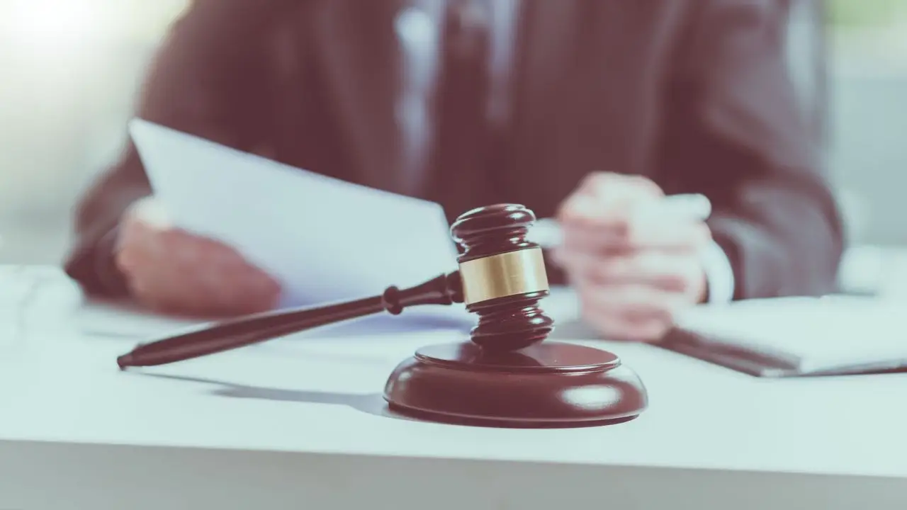 Alimenty na rodziców - młotek sędziego z prawnikiem pracującym nad dokumentem prawnym w tle